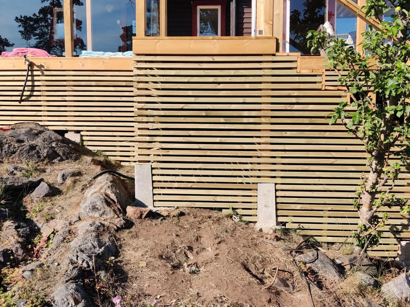 Horisontell träbeklädnad framför terrassens underbyggnad i Tyresö.